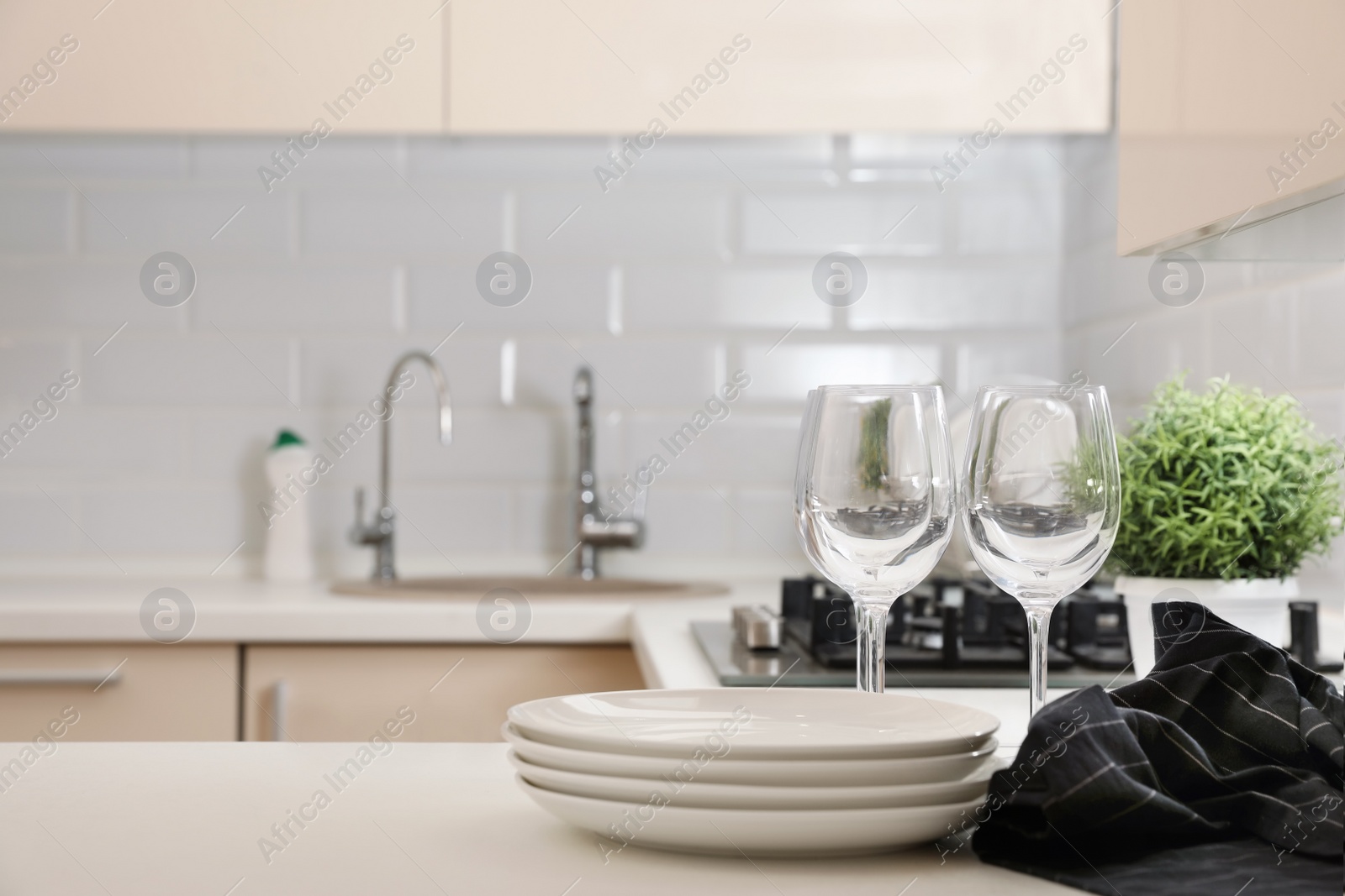 Photo of Stack of clean dishes and glasses on table in kitchen. Space for text