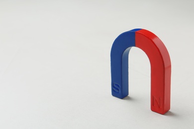 Photo of Red and blue horseshoe magnet on white background. Space for text