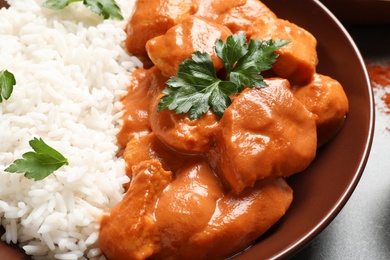 Photo of Plate of delicious butter chicken with rice on table, closeup