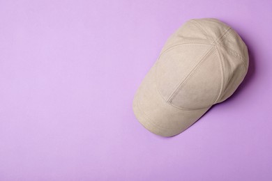 Photo of Stylish beige baseball cap on violet background, top view. Space for text