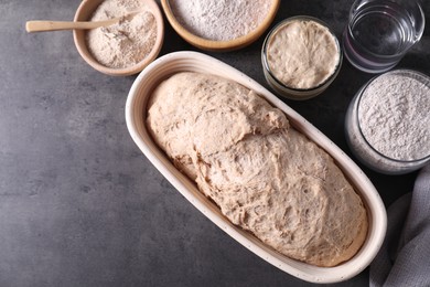 Photo of Fresh sourdough, flour and water on grey table, flat lay. Space for text