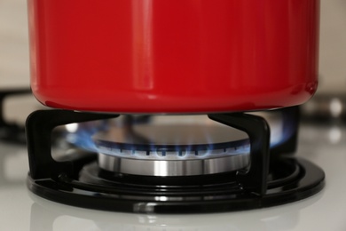 Photo of Red saucepan on modern gas stove, closeup