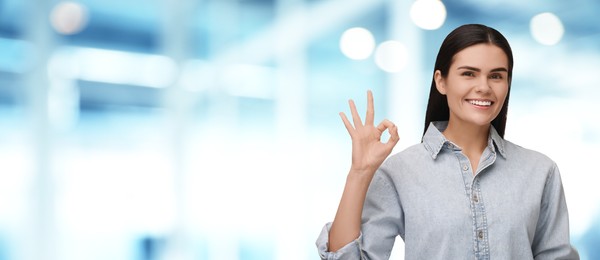 Image of Woman with clean teeth smiling and showing ok gesture on blurred background, space for text. Banner design