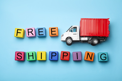 Photo of Toy truck with words FREE DELIVERY on blue background, flat lay. Logistics and wholesale concept