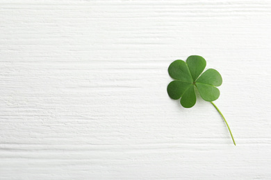 Photo of Clover leaf on white wooden table, top view with space for text. St. Patrick's Day symbol