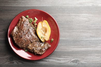 Photo of Delicious roasted beef meat, caramelized pear and thyme on grey wooden table, top view. Space for text