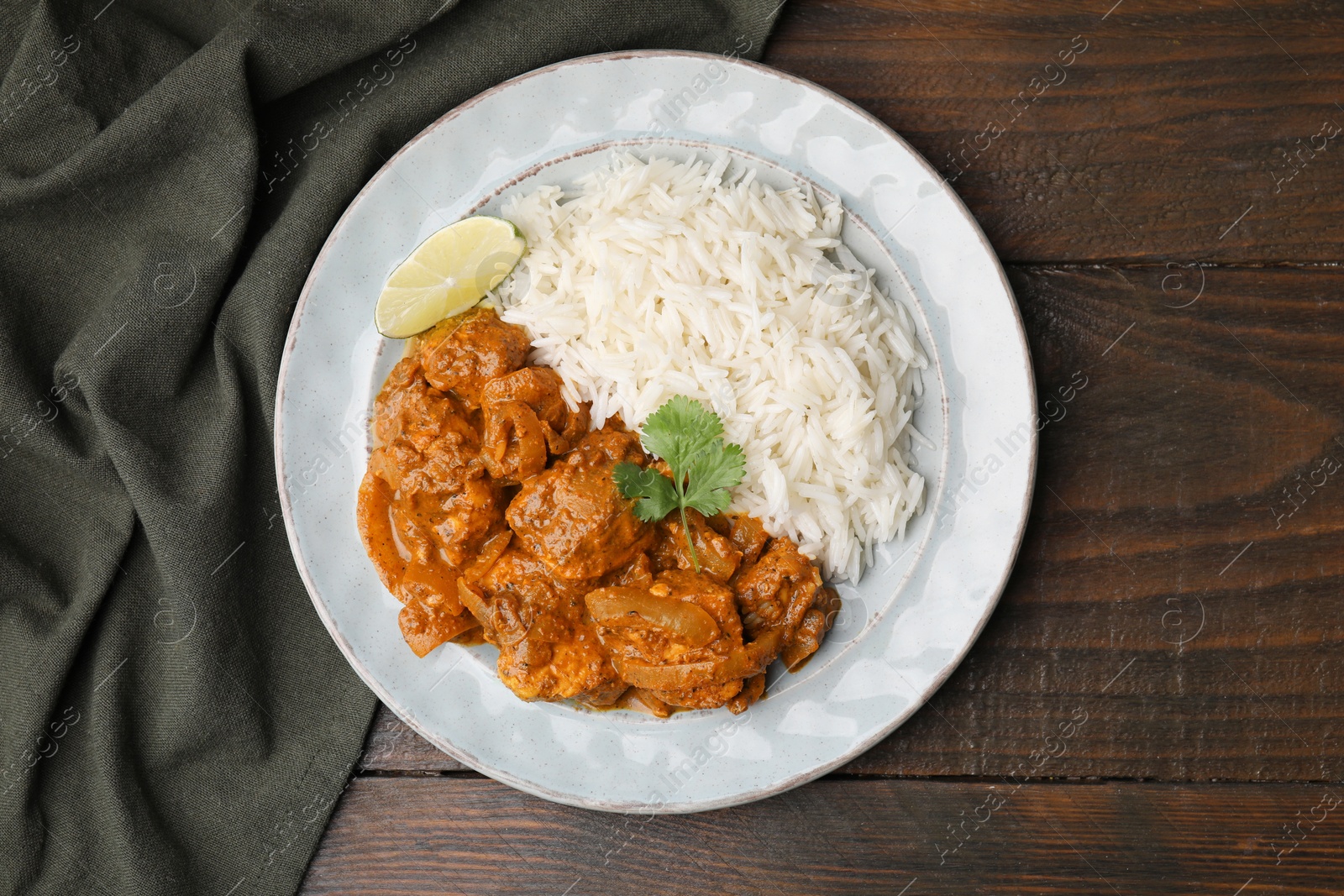 Photo of Delicious chicken curry with rice on wooden table, top view