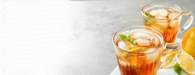 Image of Cups of refreshing iced tea on light table, space for text. Banner design