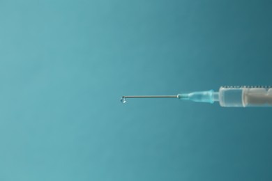 Photo of Medical syringe on light blue background, closeup. Space for text