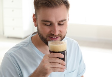 Handsome man with cold kvass indoors. Traditional Russian summer drink