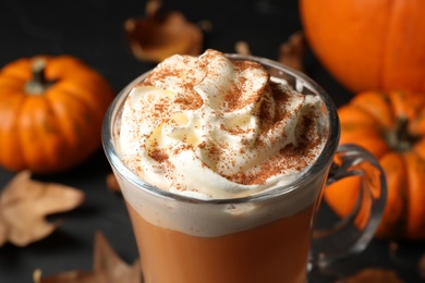 Photo of Delicious pumpkin latte with whipped cream on table, closeup