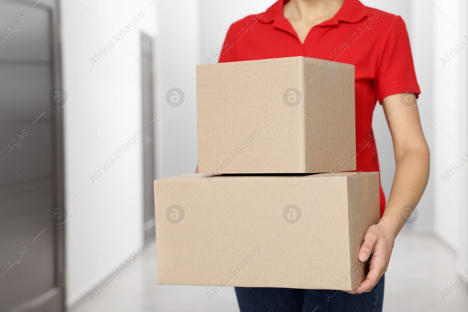 Photo of Courier with cardboard boxes in hallway, closeup