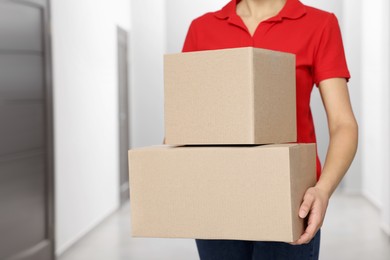 Courier with cardboard boxes in hallway, closeup