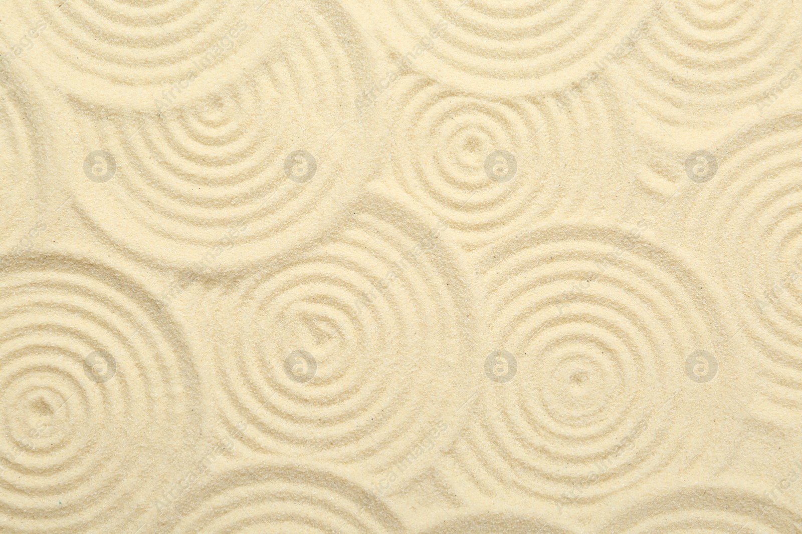 Photo of Zen rock garden. Circle patterns on beige sand, top view