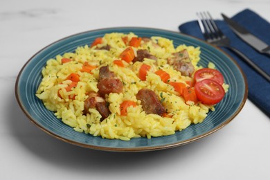 Photo of Delicious pilaf with meat served on white marble table, closeup