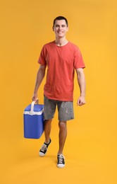 Photo of Man with blue cool box walking on orange background