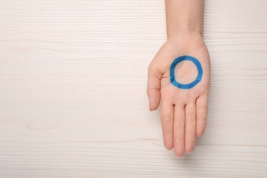 Photo of Woman showing blue circle as World Diabetes Day symbol at white wooden table, top view with space for text