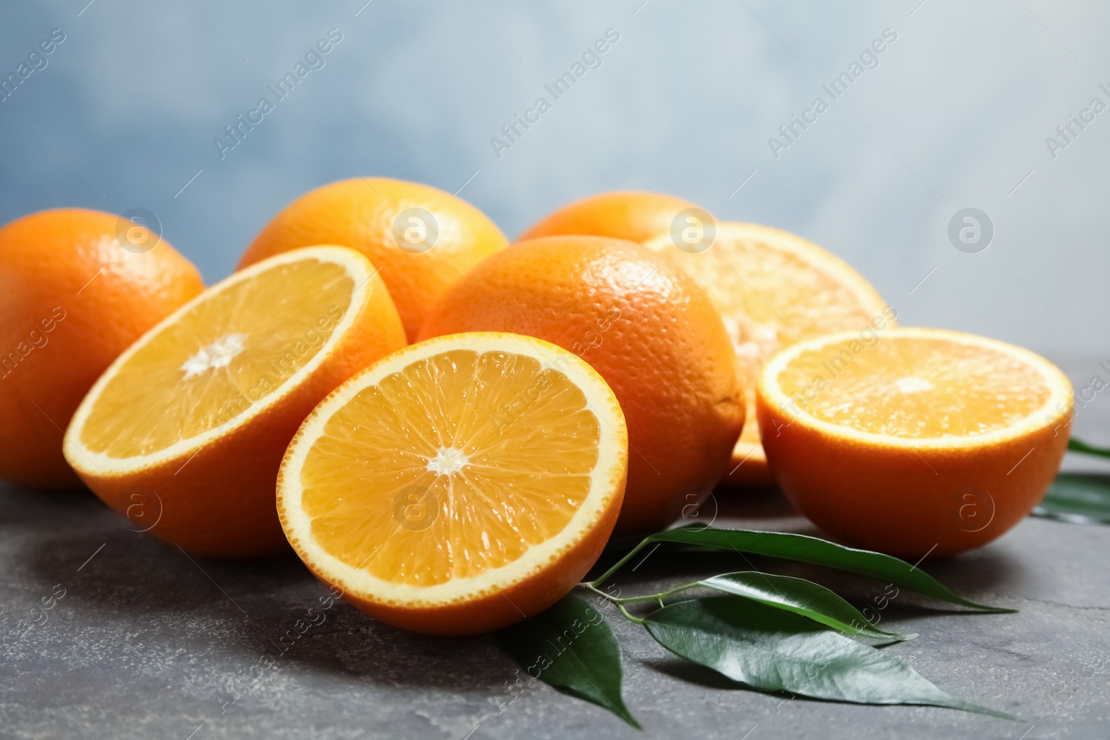 Photo of Fresh oranges with leaves on grey table