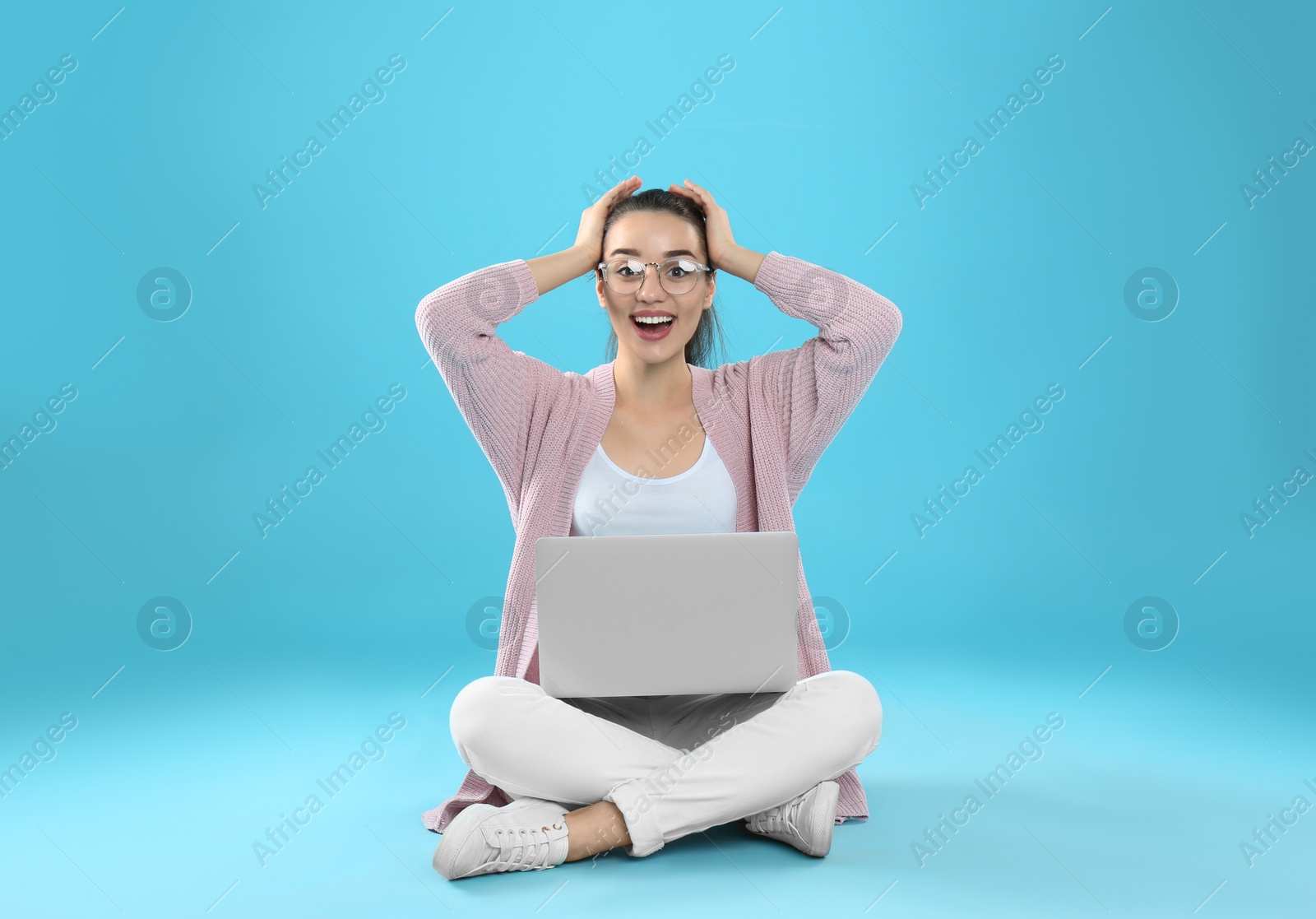 Photo of Surprised young woman in casual outfit with laptop sitting on color background