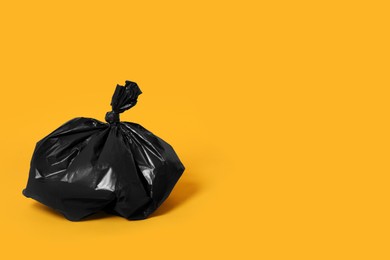 Photo of Trash bag full of garbage on orange background. Space for text
