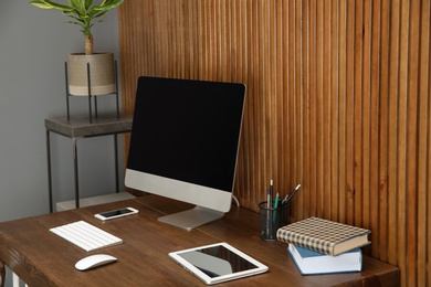 Photo of Stylish workplace with modern computer near wooden wall. Space for text
