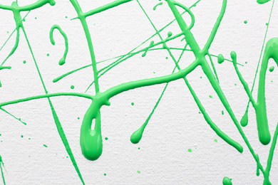 Green paint splashes on white canvas as background. Art and creativity