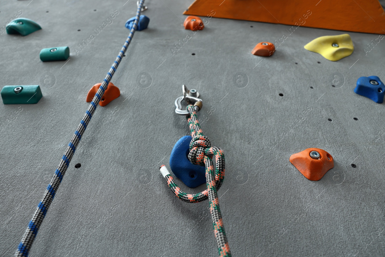 Photo of Colorful climbing wall with holds and ropes. Extreme sport