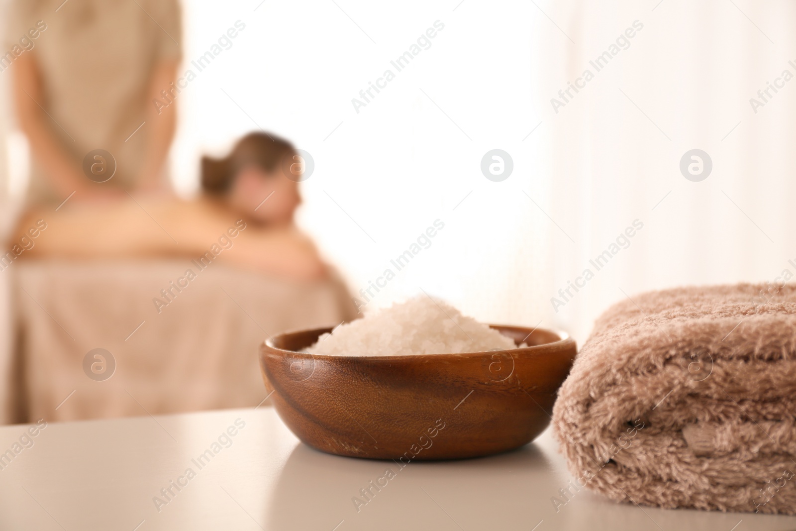 Photo of Bowl with sea salt on white table in spa salon