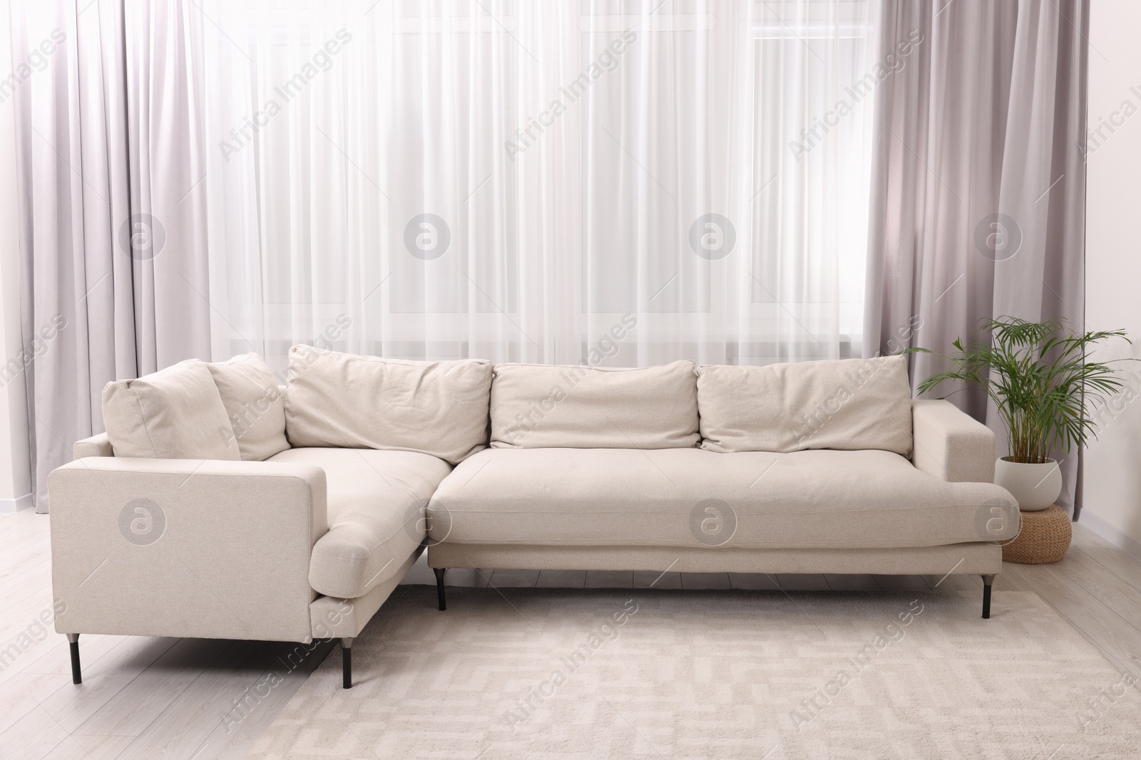 Photo of Comfortable sofa and window with beautiful curtains in room. Interior design