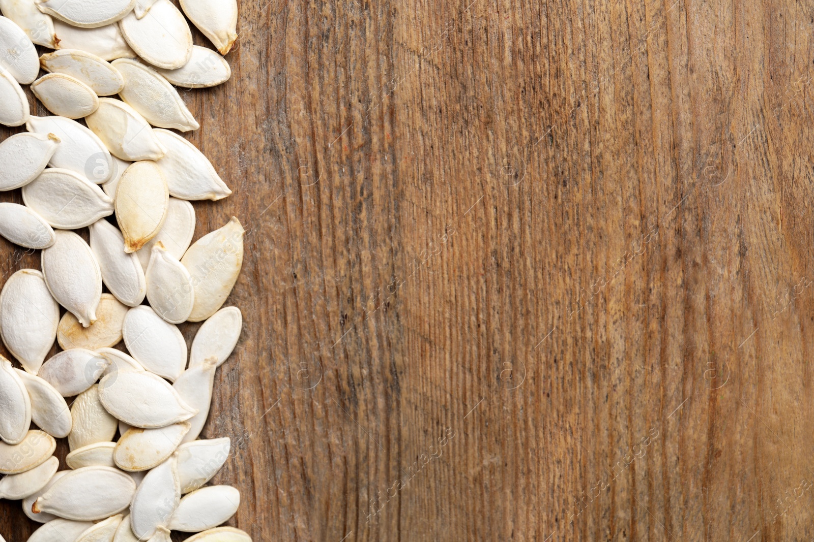 Photo of Raw pumpkin seeds and space for text on wooden background, flat lay. Vegetable planting