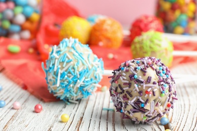 Photo of Tasty cake pops with colorful sprinkles on wooden table, space for text