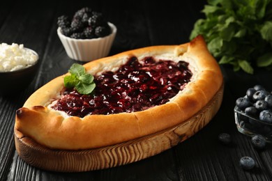 Delicious sweet cottage cheese pastry with cherry jam on black wooden table, closeup