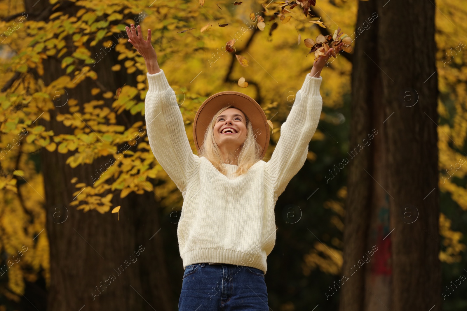 Photo of Autumn vibes. Happy woman throwing leaves up in park