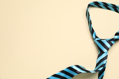 Photo of Striped necktie on beige background, top view. Space for text