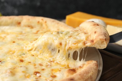 Photo of Taking piece of delicious cheese pizza at table, closeup