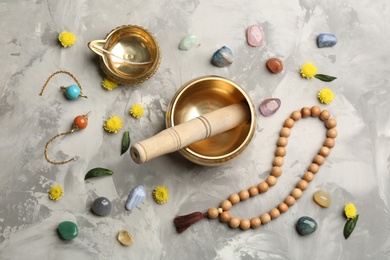 Flat lay composition with golden singing bowl on grey table. Sound healing