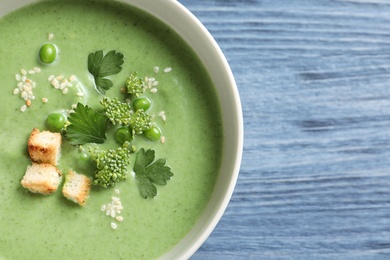 Photo of Fresh vegetable detox soup made of green peas and broccoli in dish on wooden background, top view with space for text