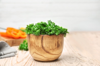 Bowl with fresh green parsley on table