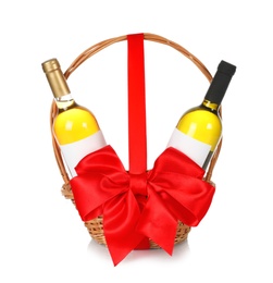 Photo of Bottles of wine in wicker basket with red bow isolated on white