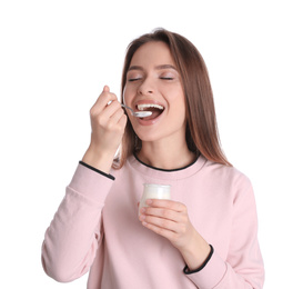 Young attractive woman eating tasty yogurt on white background