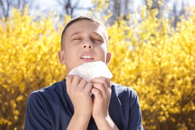 Photo of Little boy suffering from seasonal allergy outdoors on sunny day