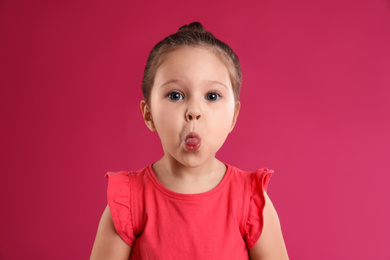 Photo of Portrait of cute little girl on pink background