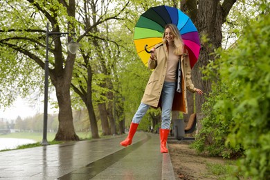 Photo of Young woman with umbrella walking in park on spring day