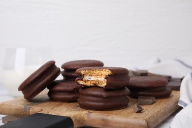Photo of Tasty choco pies and pieces of chocolate on wooden board, closeup. Space for text
