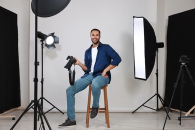 Photo of Young professional photographer with camera in modern photo studio