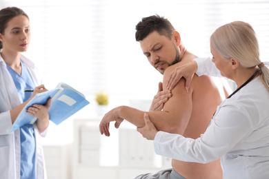 Female orthopedist examining patient's arm in clinic