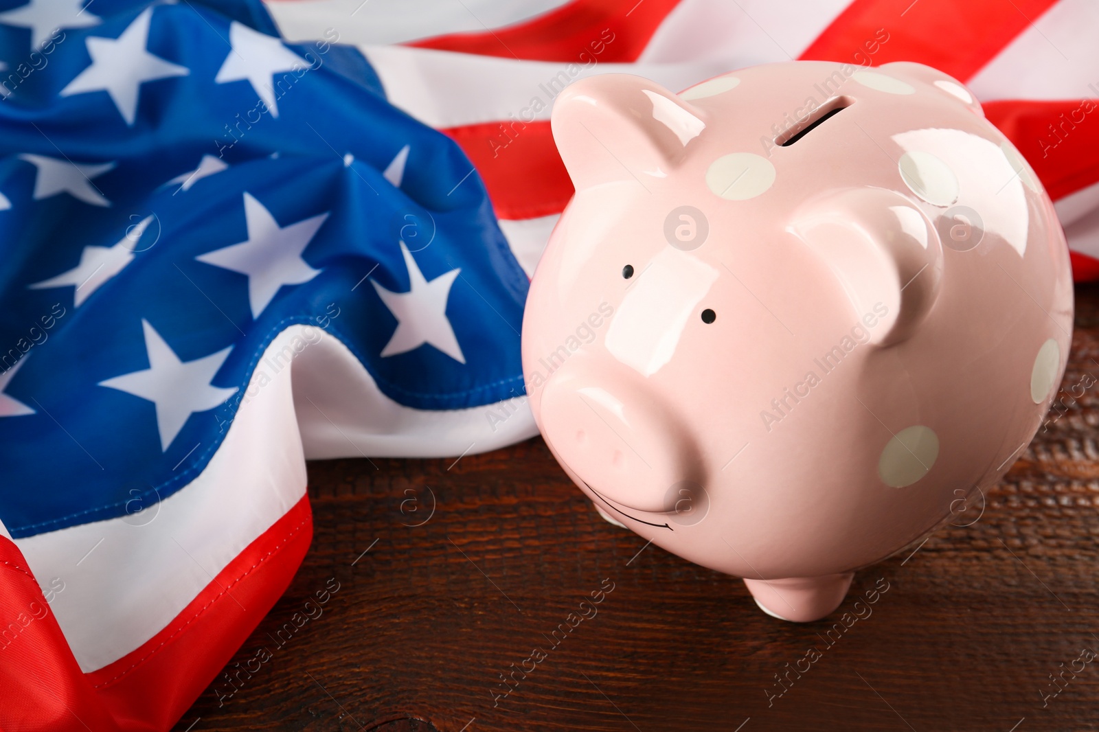 Photo of Piggy bank and American flag on wooden table, closeup