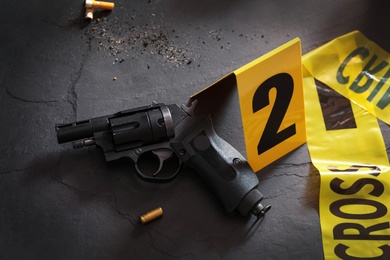 Photo of Composition with gun and shell casing on black slate table. Crime scene