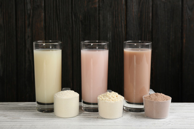 Photo of Protein shakes and powder on white wooden table