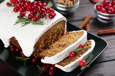 Photo of Traditional classic Christmas cake decorated with cranberries and rosemary on wooden table, closeup